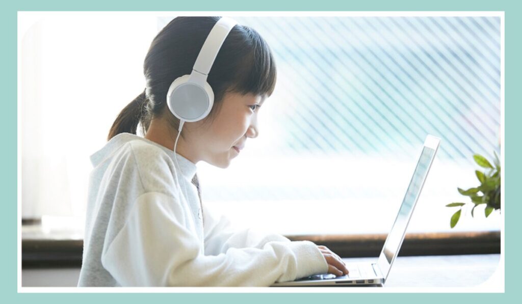 小学生の女の子がヘッドホンをつけてノートパソコンでプログラミングのオンライン授業を受けている様子。LITALICOワンダーオンラインをはじめとした小学生向けプログラミング習い事・自宅学習のイメージ